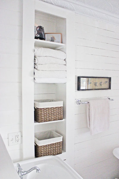 wicker-baskets-placed-in-cuby-holes-in-white-bathroom
